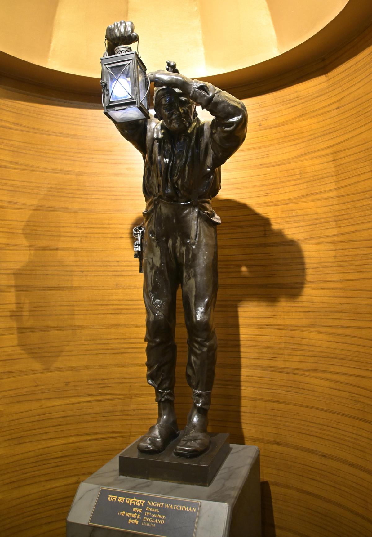 A bronze sculpture of a watchman holding a lantern and a bunch of keys