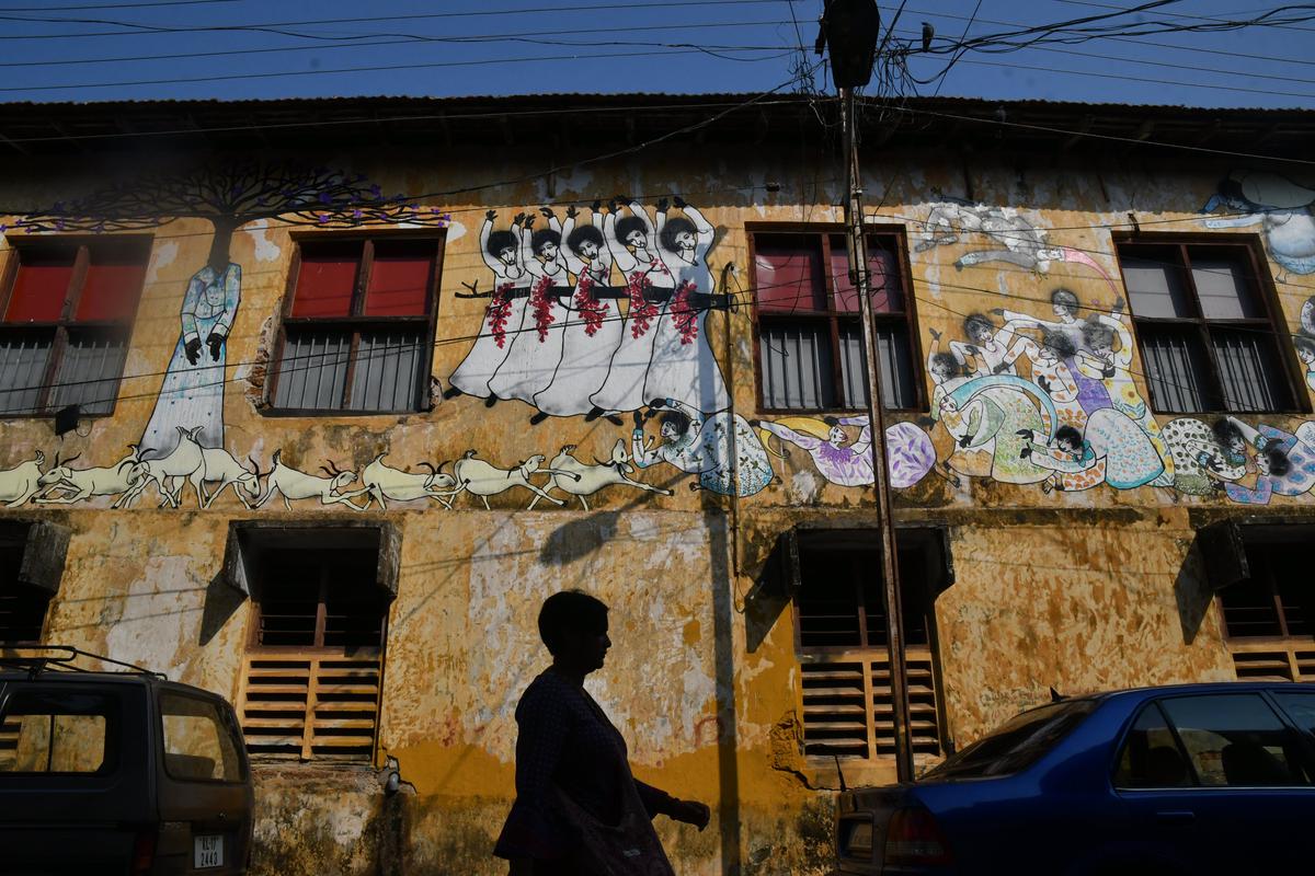     A tourist walks past a building with graffiti art drawn for the 2018 Kochi-Muziris Biennial in Fort Kochi