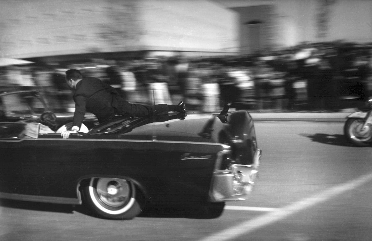  In this Nov. 22, 1963 file photo, the limousine carrying mortally wounded President John F. Kennedy races toward the hospital seconds after he was shot in Dallas. Secret Service agent Clinton Hill is riding on the back of the car, Nellie Connally, wife of Texas Gov. John Connally, bends over her wounded husband, and first lady Jacqueline Kennedy leans over the president.