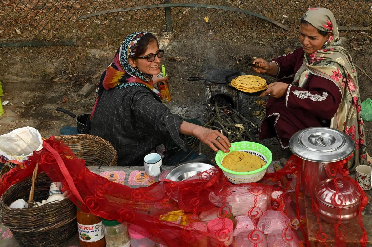 A woman prepares maize flour flatbread and sells salted tea to locals at her roadside stall in Raiyar village. 