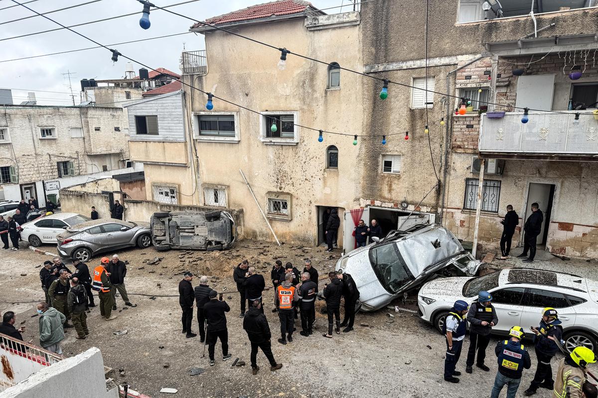 Members of the Israeli emergency services, security officials and onlookers gather at the missile impact site, after Iranian missile barrages were launched at Israel, amid the U.S.-Israel conflict with Iran, in central Israel, on March 26, 2026