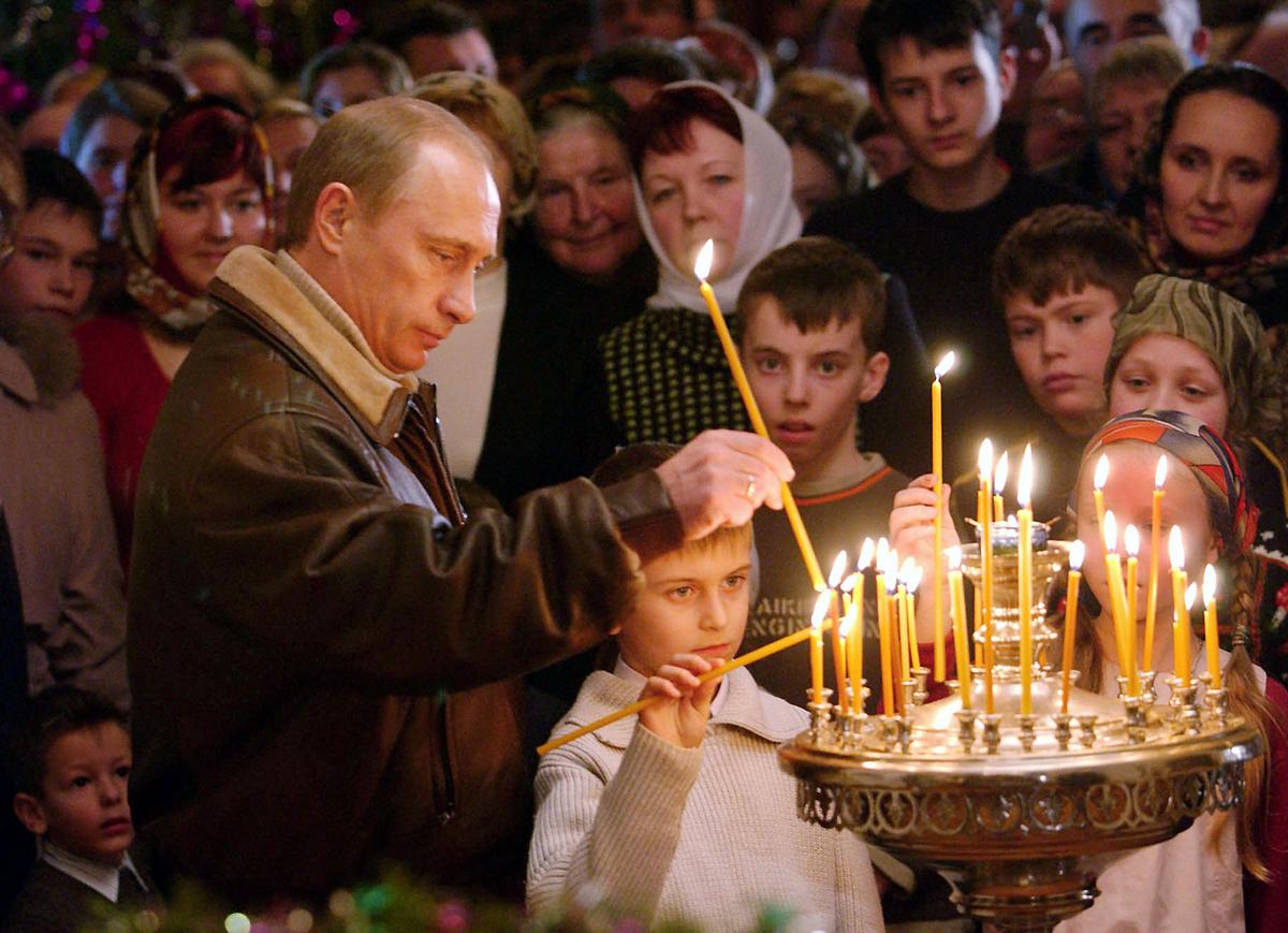 Russian President Vladimir Putin, left,  places a candle as he attends Christmas service in the ancient Church of the Nativity of the Virgin, in Gorodnya in the Tver region, about 135 km (84 miles) northwest of Moscow, on January 7, 2005. 