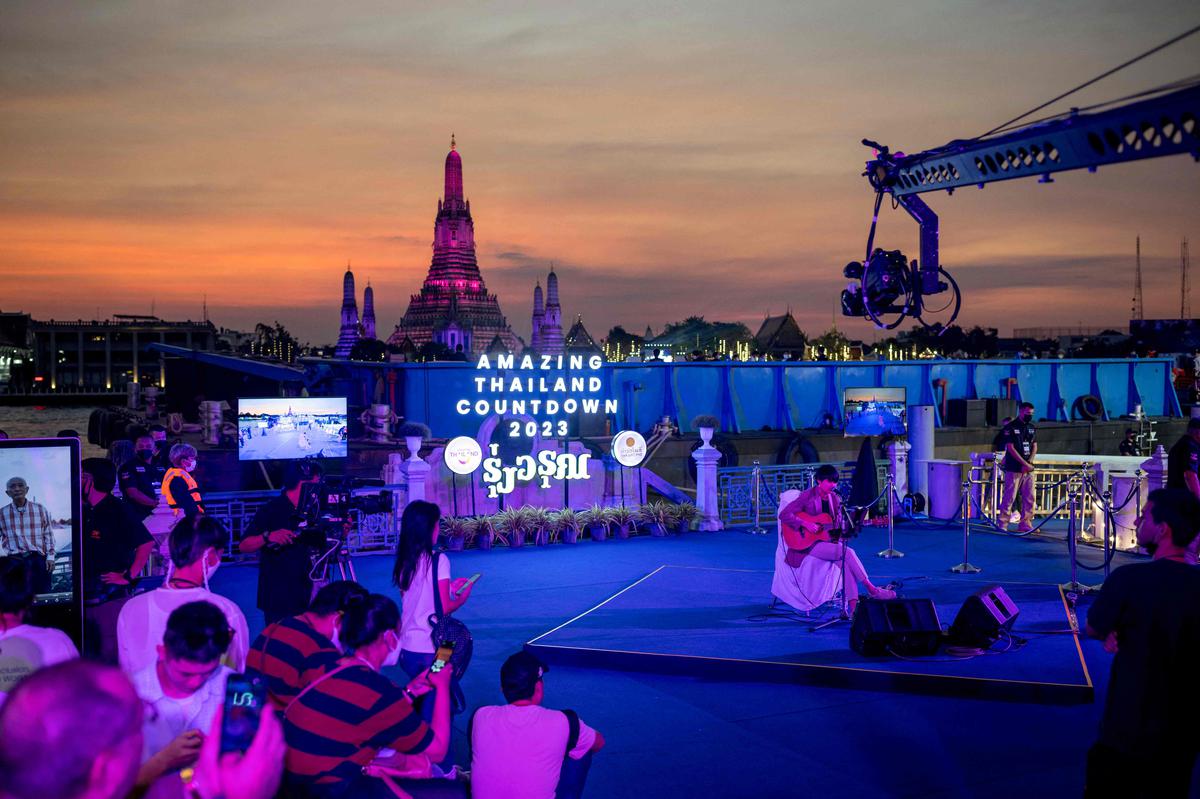 A performer sings during New Year countdown celebrations along the Chao Phraya River opposite Wat Arun Buddhist temple in Bangkok on December 31, 2022.