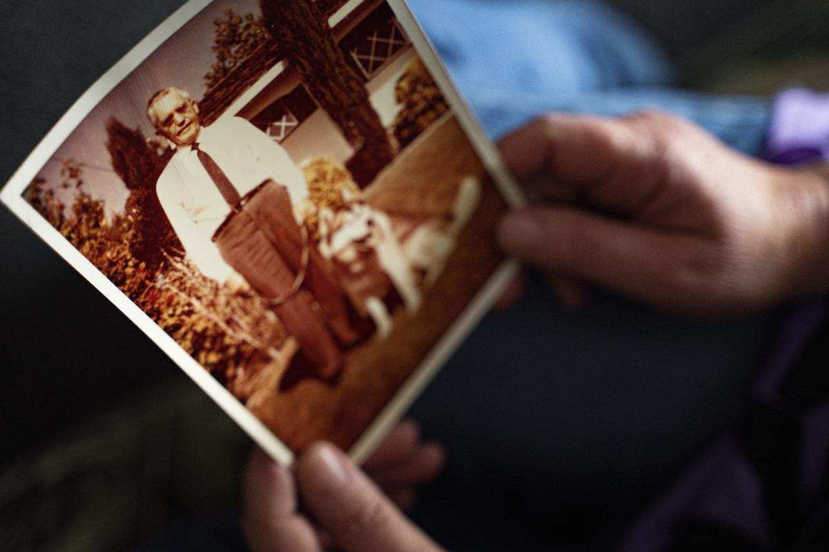 Pam Walton, a former “Two by Twos” sect member who helps track movements of allegedly predatory members through photographs and documents, holds a photograph of a deceased spiritual leader of the sect at a library. 