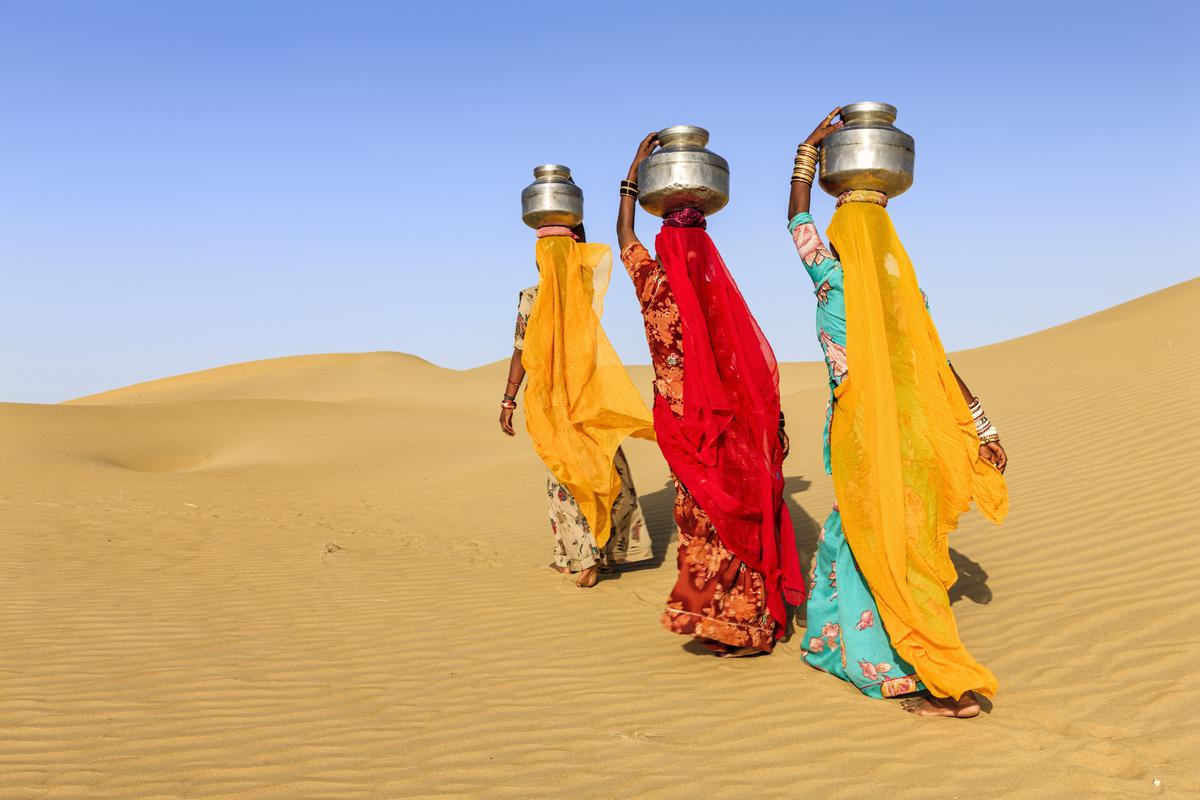 Women wearing bright reds and oranges in scorching Rajasthan.