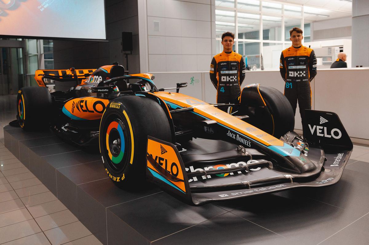 A handout picture released on February 13, 2023, by McLaren shows British driver Lando Norris (left) and McLaren’s Australian driver Oscar Piastri posing beside the McLaren MCL60 Formula One racing car for the 2023 season at their base in Woking, west of London. 