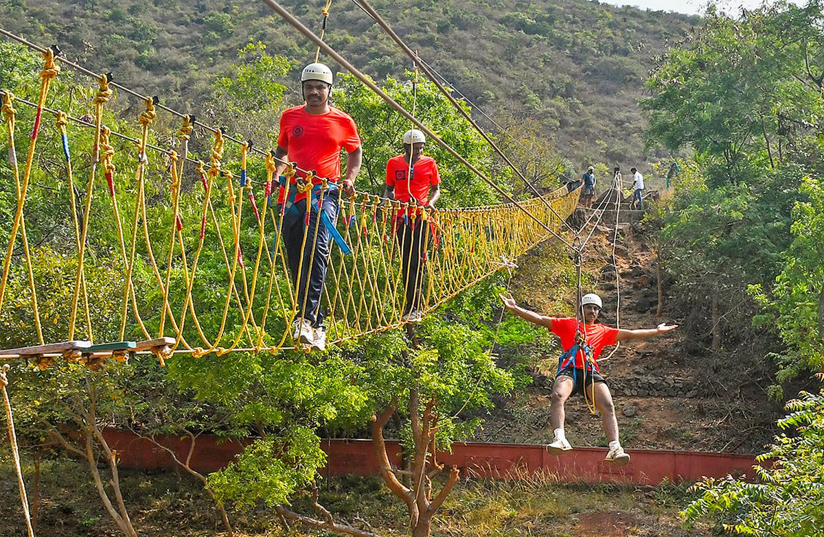 People enjoying Burma bridge and zipline at the adventure sports zone in Kambalakonda Eco Tourism Park.