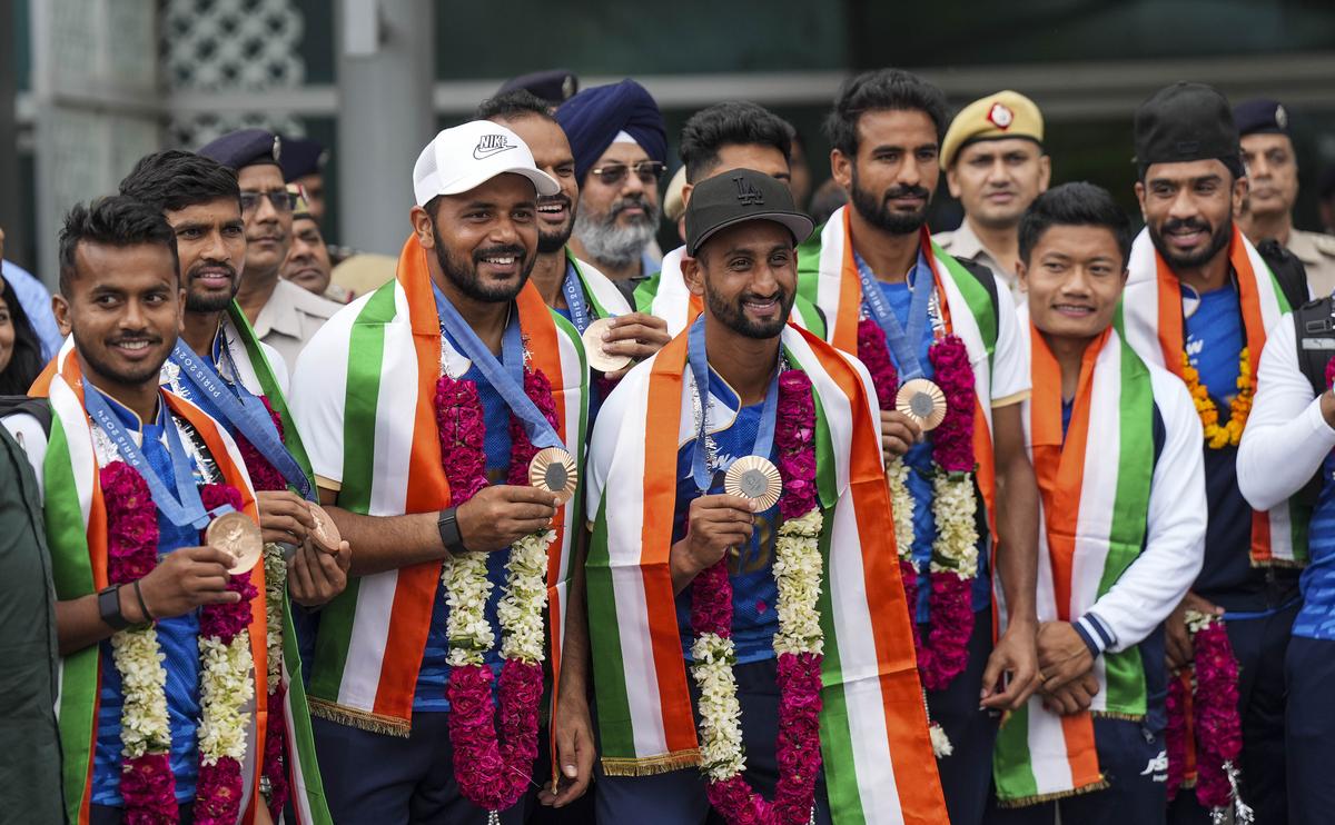 Paris Olympic Bronze medalist Indian Hockey players pose for photos on their arrival at the Indira Gandhi International Airport, in New Delhi, Saturday, Aug. 10, 2024