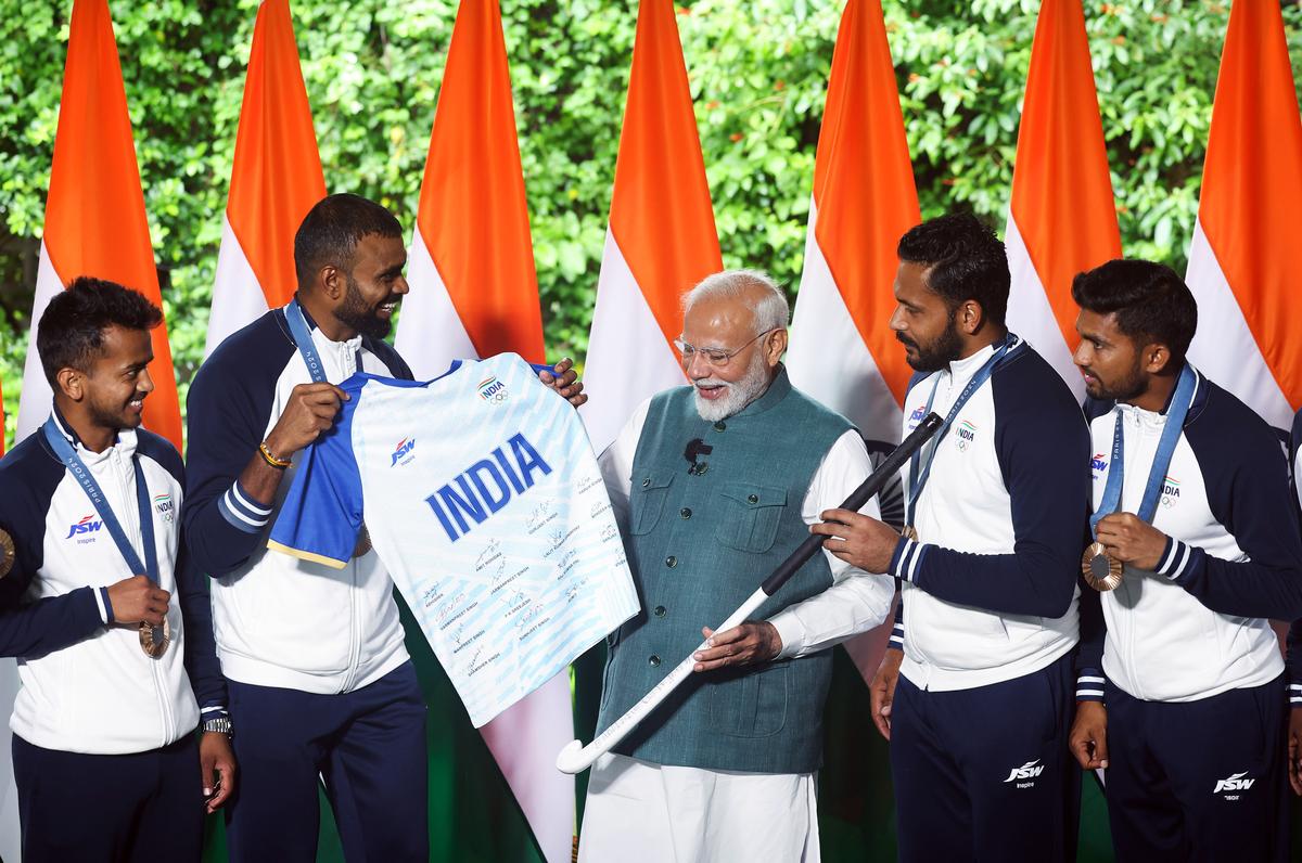 Prime Minister Narendra Modi being presented with a hockey stick and Team jersey by hockey captain Harmanpreet Singh during his meeting with India’s men’s Hockey team of the Paris Olympics 2024, in New Delhi on Thursday. 