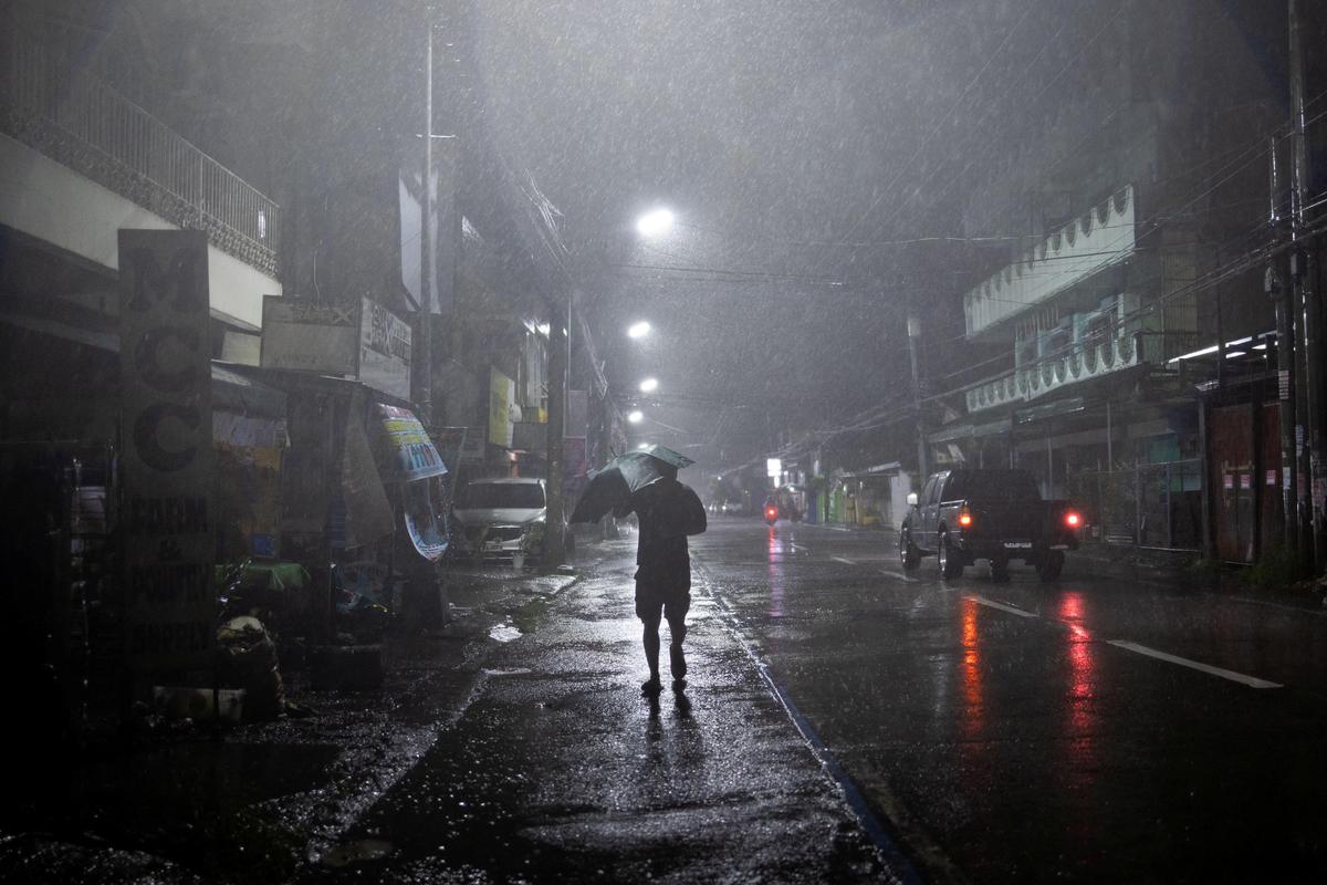 A man walks in the rain with an umbrella as Typhoon Fung-wong approaches, in Cauayan, Isabela, Philippines, on November 9, 2025.