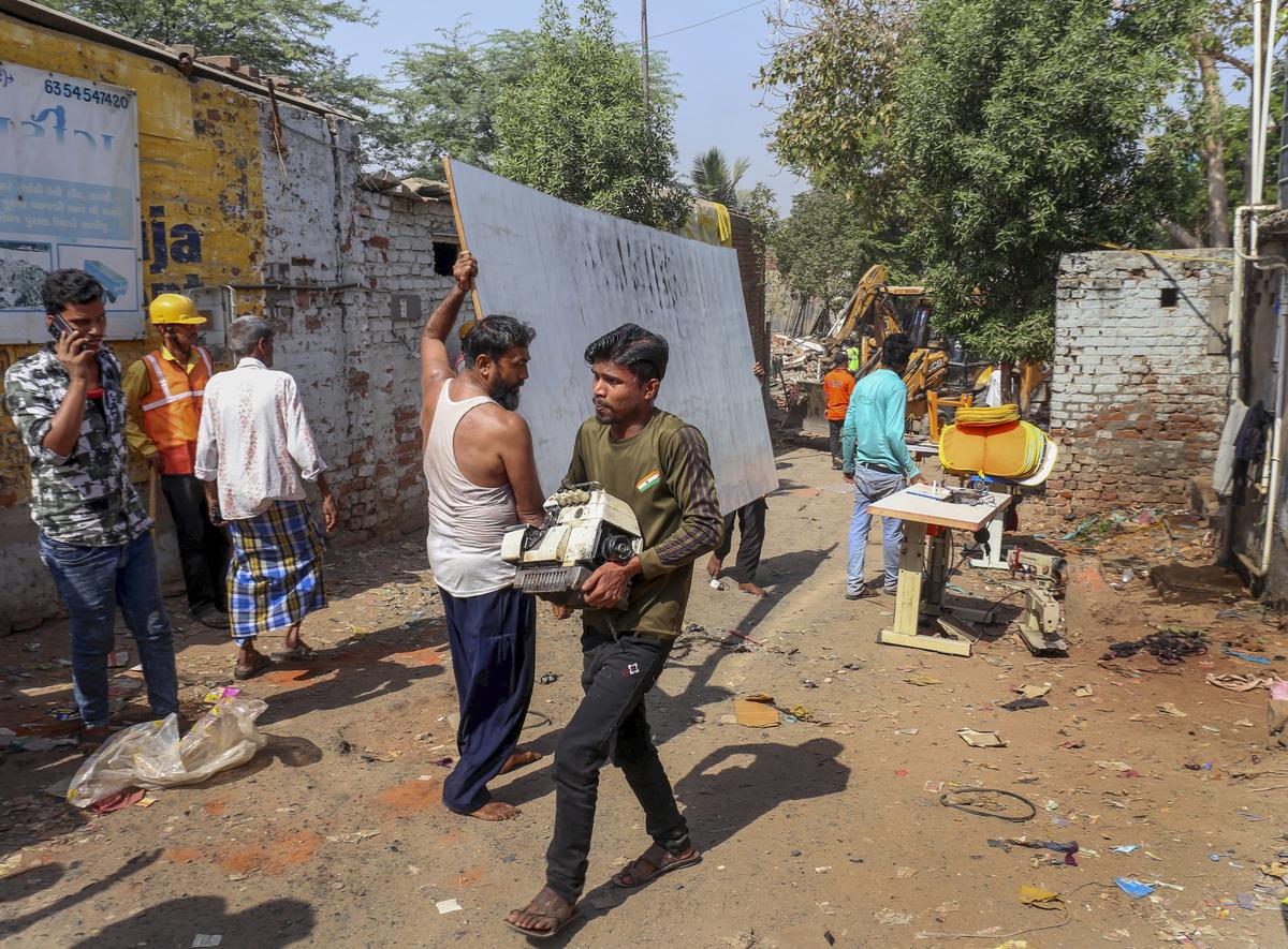 People carry belongings during a demolition drive by the Amdavad Municipal Corporation near Chandola lake on April 29, 2025. People carry belongings during a demolition drive by the Amdavad Municipal Corporation near Chandola lake on April 29, 2025.