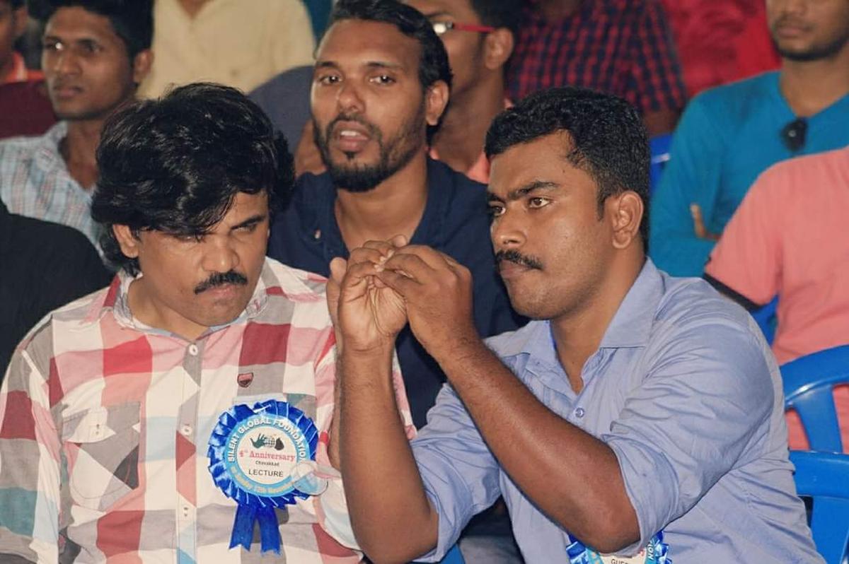 Sign language interpreter Vinayachandran BS interpreting for a visually challenged-cum-hearing impaired person at an event 