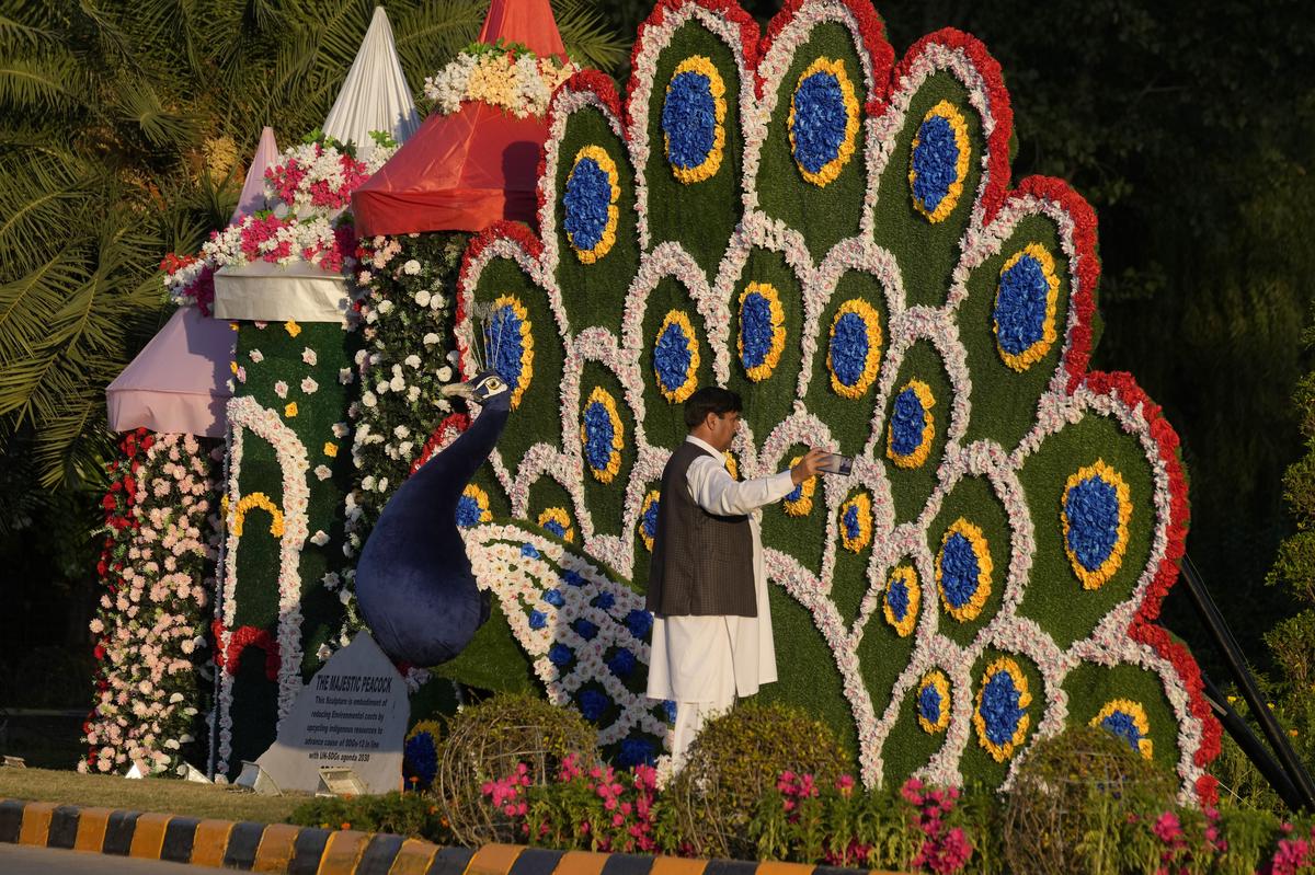 A man takes a photo with a display of floral artwork 'Mayur' near the venue of the upcoming Shanghai Cooperation Organization (SCO) summit in Islamabad.