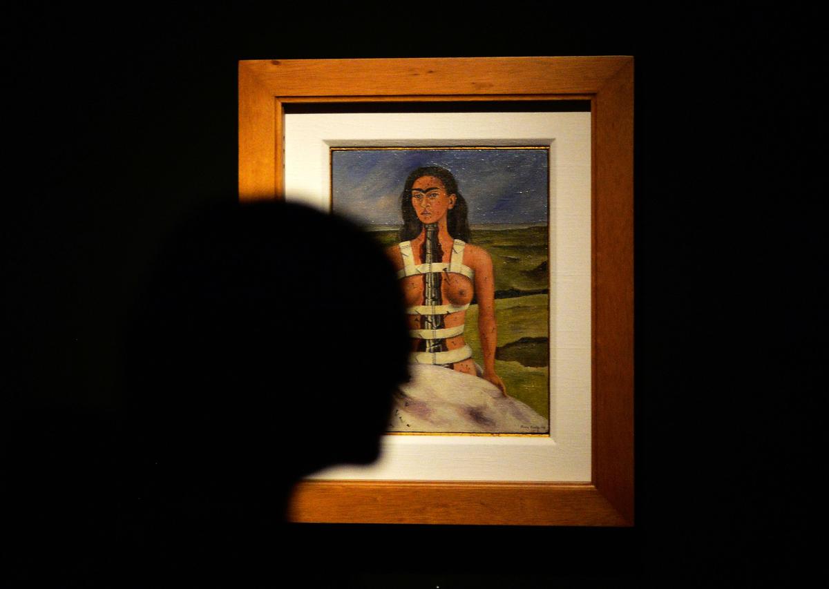 A woman walks by the painting The Broken Column (1944) by Frida Kahlo A woman walks by the painting The Broken Column (1944) by Frida Kahlo