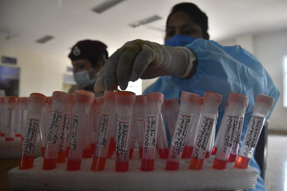 A healthcare worker and a Delhi Civil Defence volunteer collect swab samples from passengers for an RT-PCR test at Delhi Cantt railway station in New Delhi during the Covid-19 pandemic.