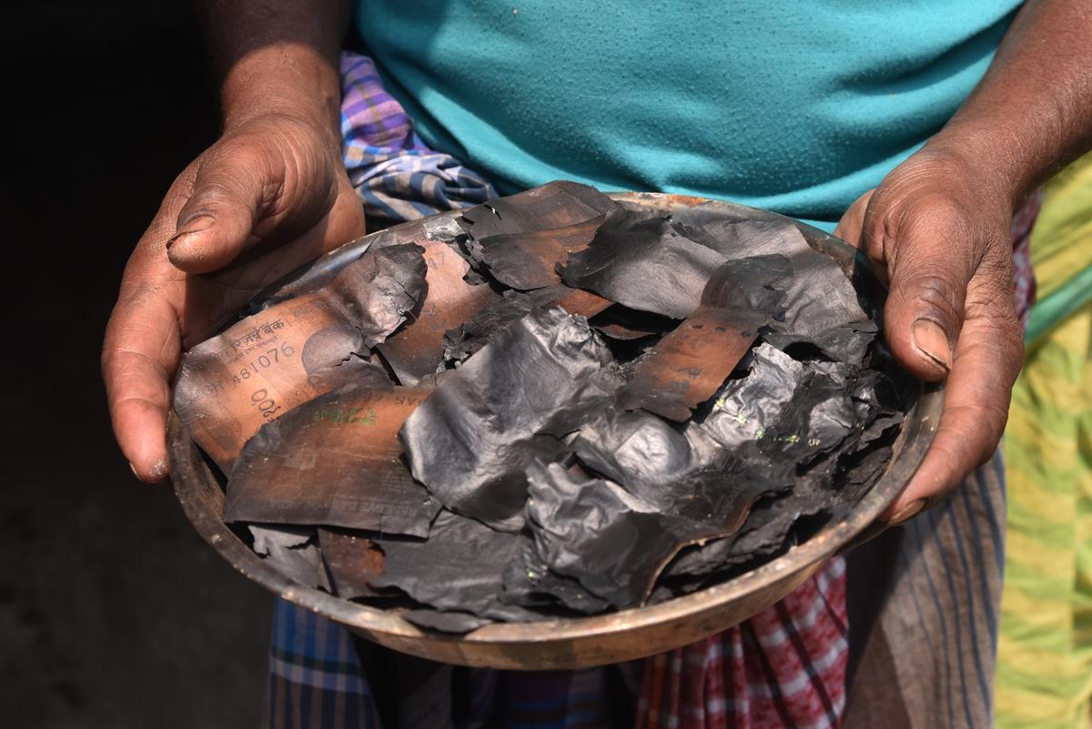 A resident of Betbona village shows burnt currency. 