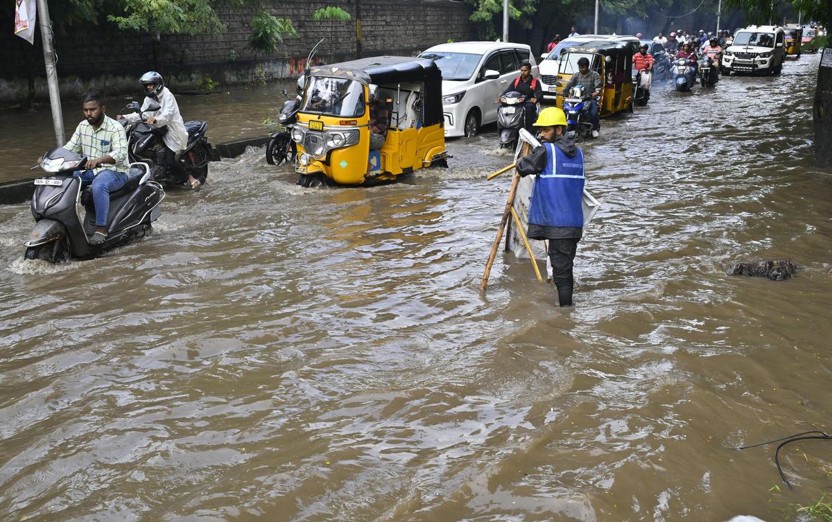 हैदराबाद में भारी बारिश के बाद जलजमाव वाली सड़क से गुजरते हुए वाहन चालक।