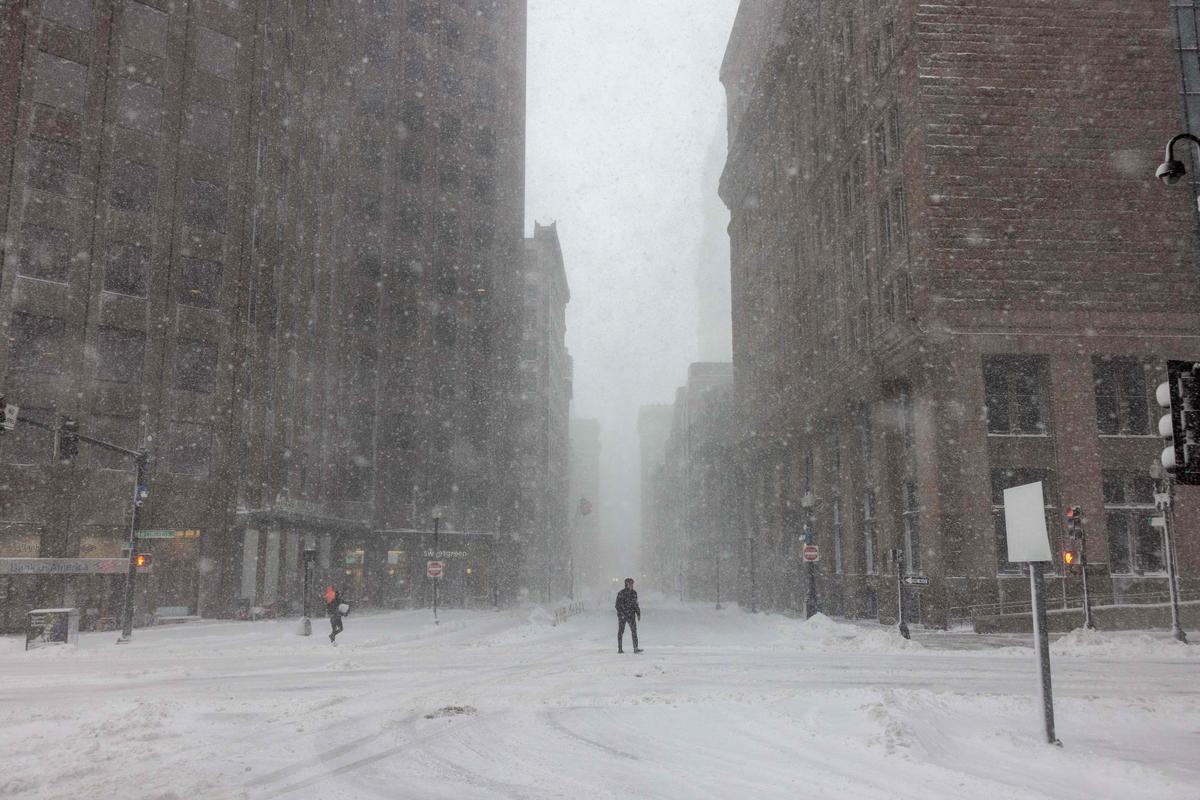 Le persone attraversano la strada durante forti venti e forti nevicate il 23 febbraio 2026 a Boston, Massachusetts