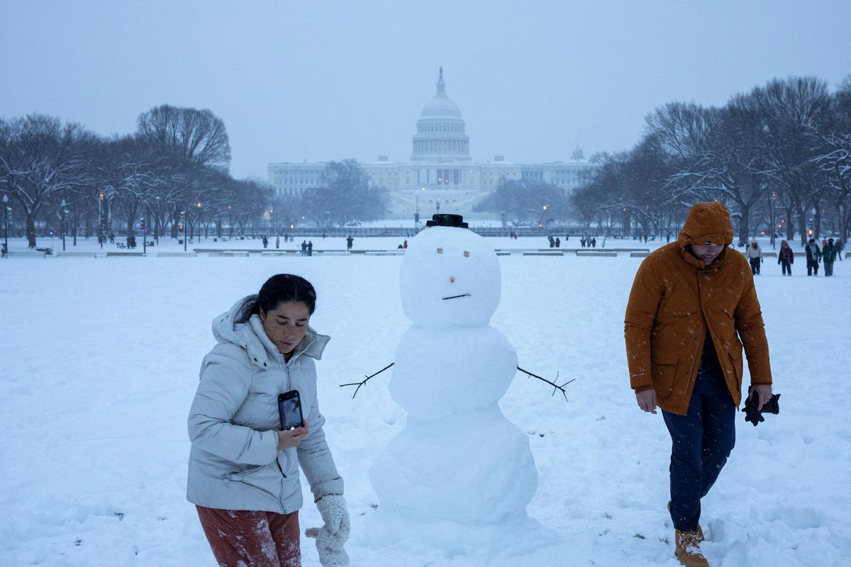 People walk next to a snowman near the U.S. Capitol, on the day of a joint session of the Congress to certify Donald Trump's election, as a winter storm that brought snow, ice and freezing temperatures to a broad swath of the U.S. arrived, in Washington, U.S. January 6, 2025. REUTERS/Marko Djurica