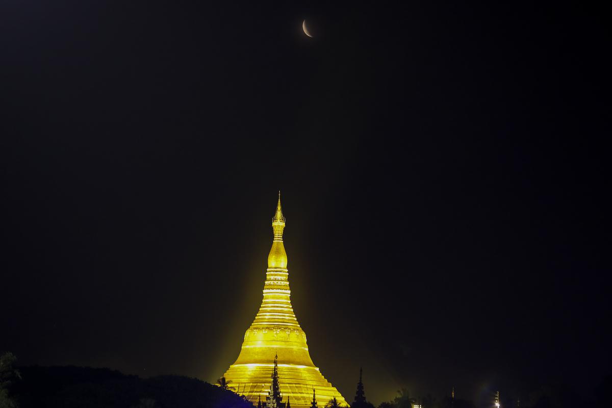 The moon rises above Myanmar Landmark Shwedagon pagoda during a lunar eclipse in Yangon, Myanmar.