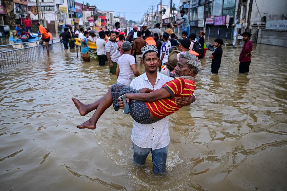 A youth carries an elderly man as they wade through a flooded street after heavy rainfall in Wellampitiya on the outskirts of Colombo on November 30, 2025. The death toll from floods and landslides triggered by Cyclone Ditwah has risen to at least 334 people across Sri Lanka, with nearly 400 still missing, the Disaster Management Centre said on November 30. (Photo by Ishara S. KODIKARA / AFP) A youth carries an elderly man as they wade through a flooded street after heavy rainfall in Wellampitiya on the outskirts of Colombo on November 30, 2025. The death toll from floods and landslides triggered by Cyclone Ditwah has risen to at least 334 people across Sri Lanka, with nearly 400 still missing, the Disaster Management Centre said on November 30. (Photo by Ishara S. KODIKARA / AFP)
