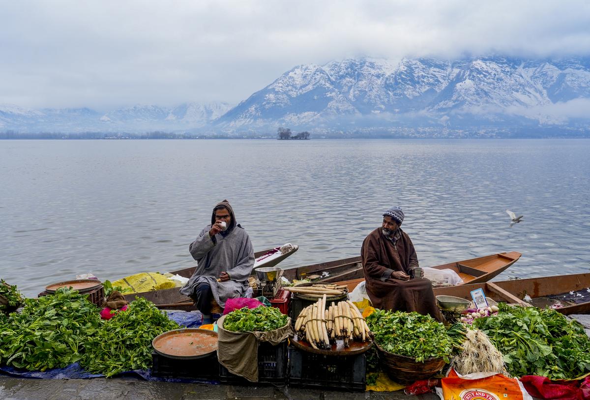 Vegetable sellers wait for customers on the bank of Dal Lake in the backdrop of ranges covered in fresh snowfall, in Srinagar. Vegetable sellers wait for customers on the bank of Dal Lake in the backdrop of ranges covered in fresh snowfall, in Srinagar.