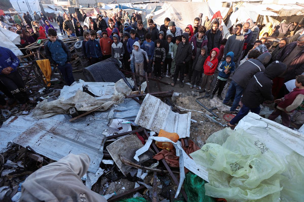 Palestinians inspect the damage at a tent camp sheltering displaced people, following an Israeli strike, amid the Israel-Hamas conflict, in Deir Al-Balah in the central Gaza Strip, December 15, 2024.