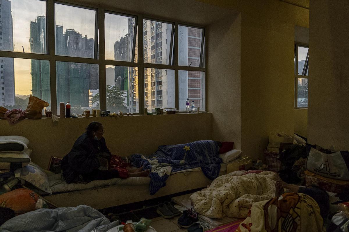 Moradores descansam perto de edifícios queimados em Wang Fuk Court, um conjunto residencial no distrito de Tai Po, nos Novos Territórios de Hong Kong, na sexta-feira, 28 de novembro de 2025.