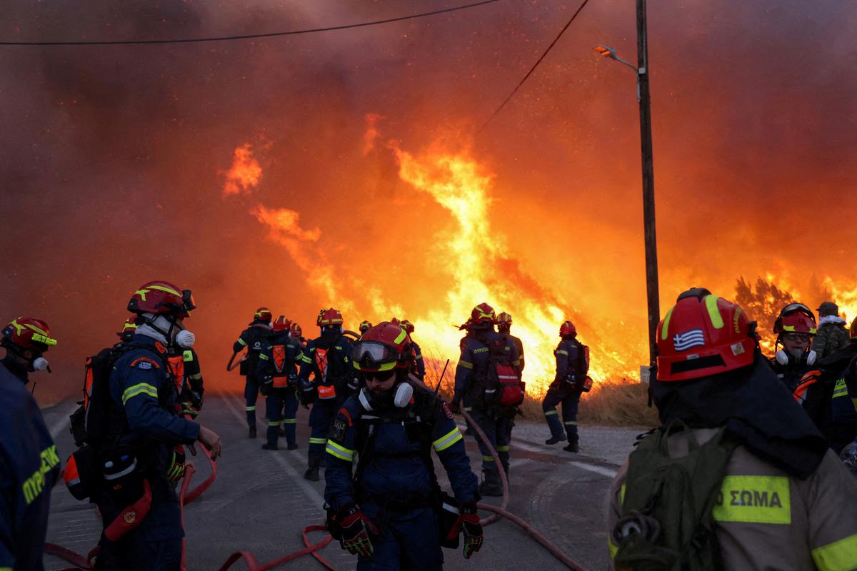 Firemen work to extinguish a wildfire, fanned by strong winds, which led to evacuation messages near the village of Karyes on Chios island, Greece, on June 22, 2025.  