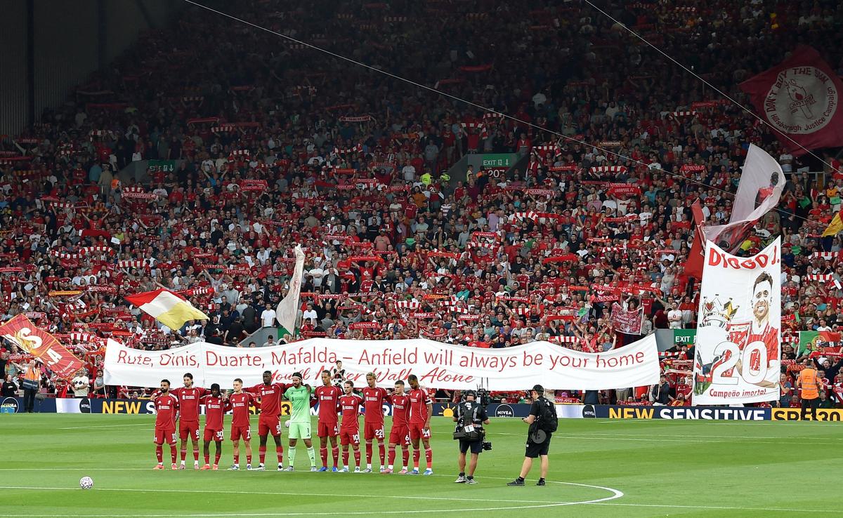 Fans display a banner as Liverpool players stand for a minute’s silence in tribute to Liverpool’s Diogo Jota and his brother Andre Silva before the match