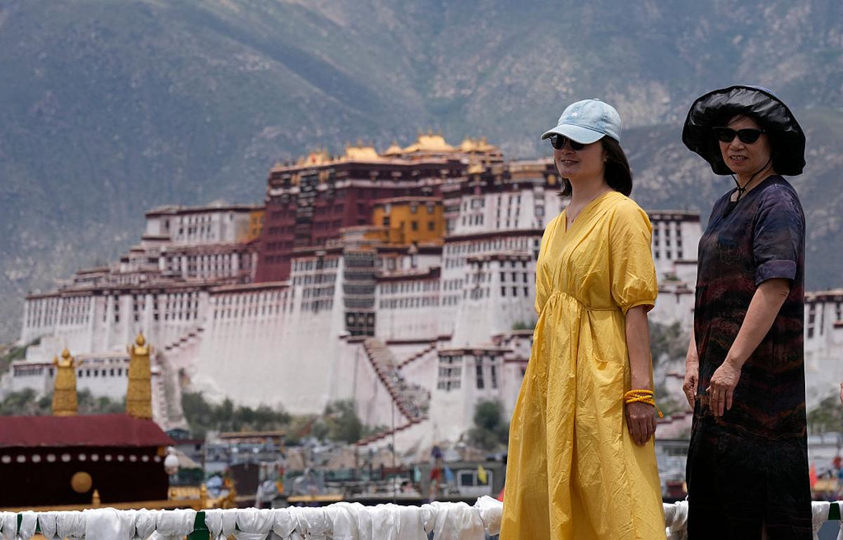 Tourists pose for a photo with the Potala Palace in the background, in Lhasa, June 2025.