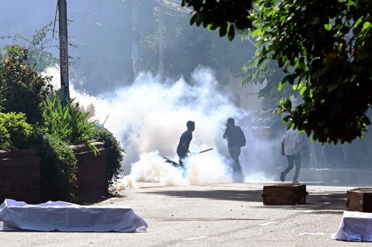 Bangladesh police personnel fire tear shells as students protest against quotas in government jobs alongside symbolic coffins of victims who died in a clash with the police,  during their absentee funeral prayer ceremony at Dhaka University in the capital on July 17, 2024. Bangladeshi students on July 17, mourned classmates killed in protests over civil service hiring rules, a day after the government ordered the indefinite closure of schools nationwide to restore order. 