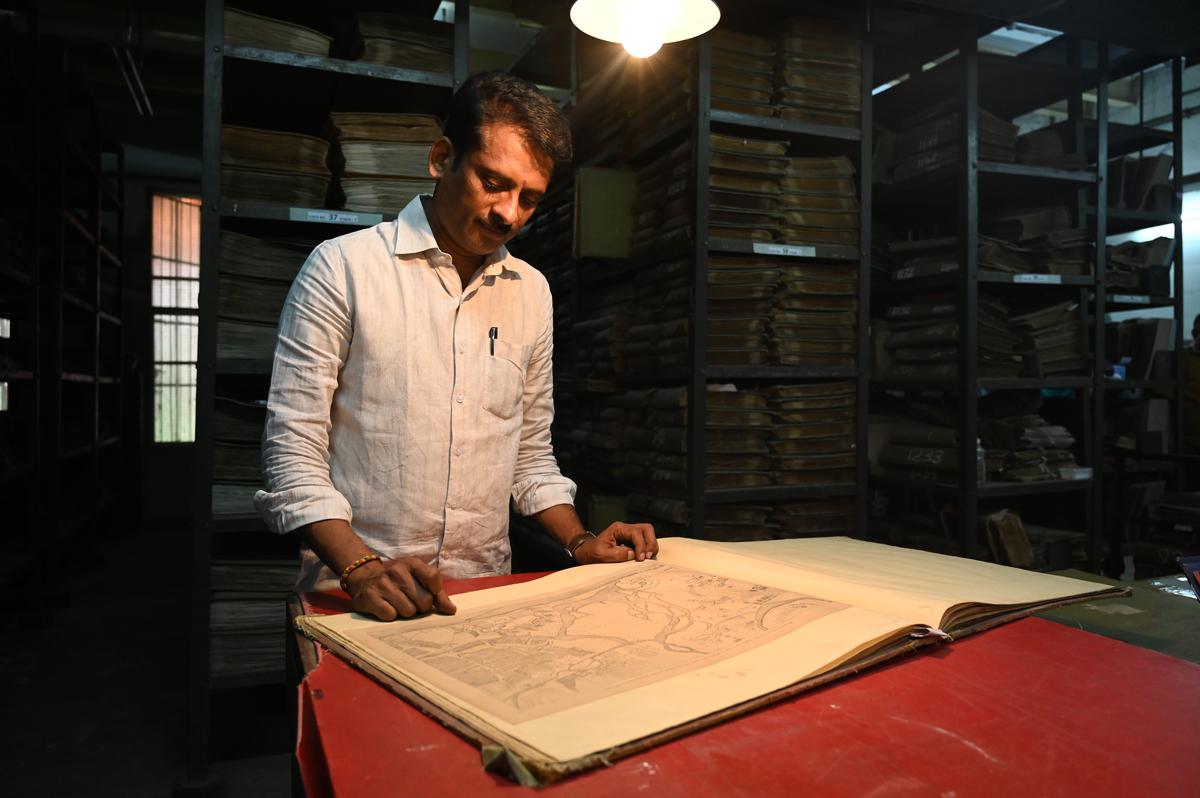 Assistant Commissioner P Vijayaraja poring over a book of old maps at the archives 