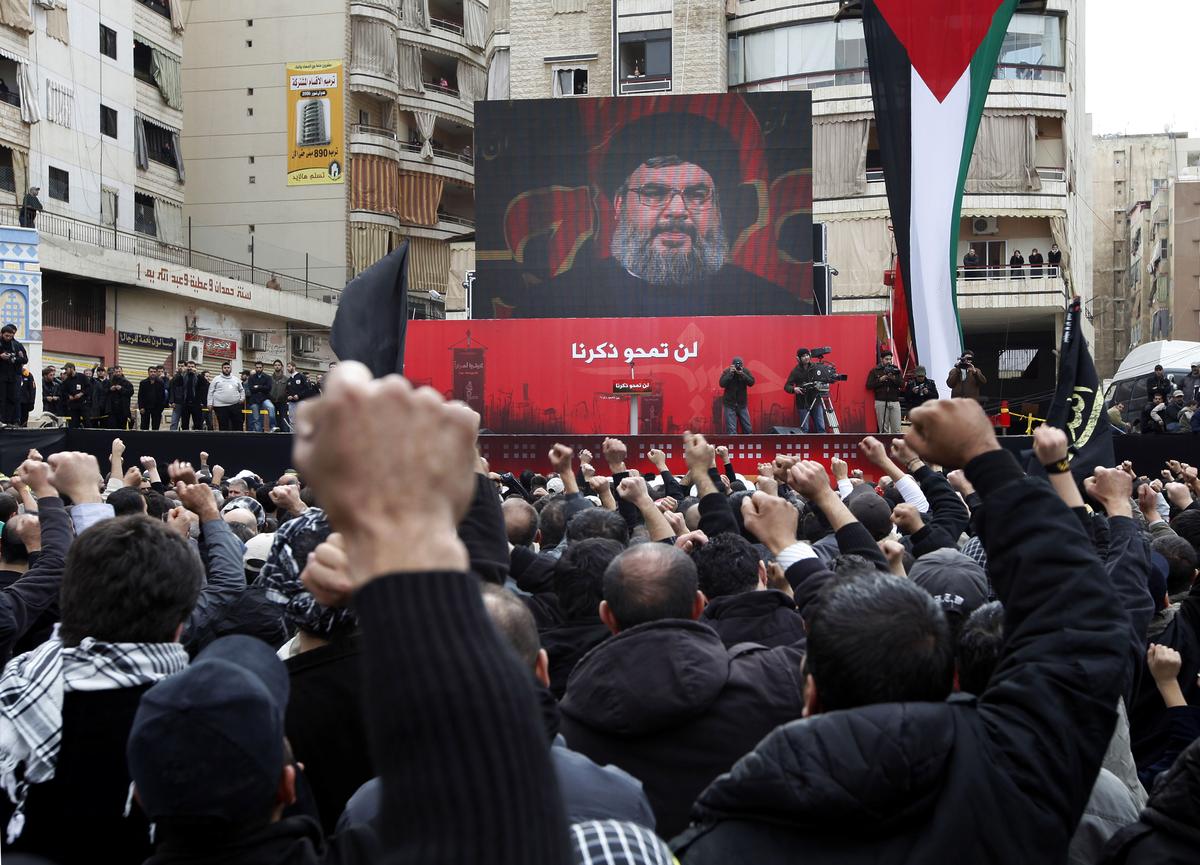 Lebanese Hezbollah supporters, raise their fists as they listen to Hezbollah’s leader Sheik Hassan Nasrallah speak, seen on a giant screen in the suburbs of Beirut, Lebanon in 2009. 