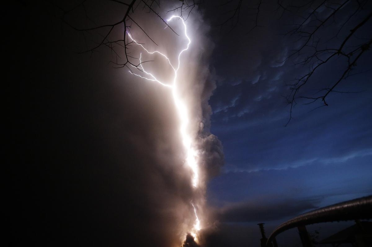 Lightning flashes as Taal Volcano erupts Sunday Jan. 12, 2020, in Tagaytay, Cavite province, outside Manila, Philippines.  A tiny volcano near the Philippine capital that draws many tourists for its picturesque setting in a lake belched steam, ash and rocks in a huge plume Sunday, prompting thousands of residents to flee and officials to temporarily suspend flights. 