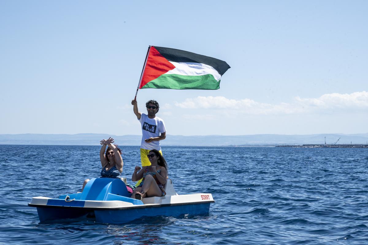 At sea, a young man raises the Palestinian flag from a pedal boat, accompanied by two smiling women on June 01, 2025 in Catania, Italy. Swedish activist Greta Thunberg is among those who will attempt to sail to Gaza on a boat organized by the Freedom Flotilla Coalition (FFC), in a bid to break Israel’s blockade of the Palestinian territory. At sea, a young man raises the Palestinian flag from a pedal boat, accompanied by two smiling women on June 01, 2025 in Catania, Italy. Swedish activist Greta Thunberg is among those who will attempt to sail to Gaza on a boat organized by the Freedom Flotilla Coalition (FFC), in a bid to break Israel’s blockade of the Palestinian territory.