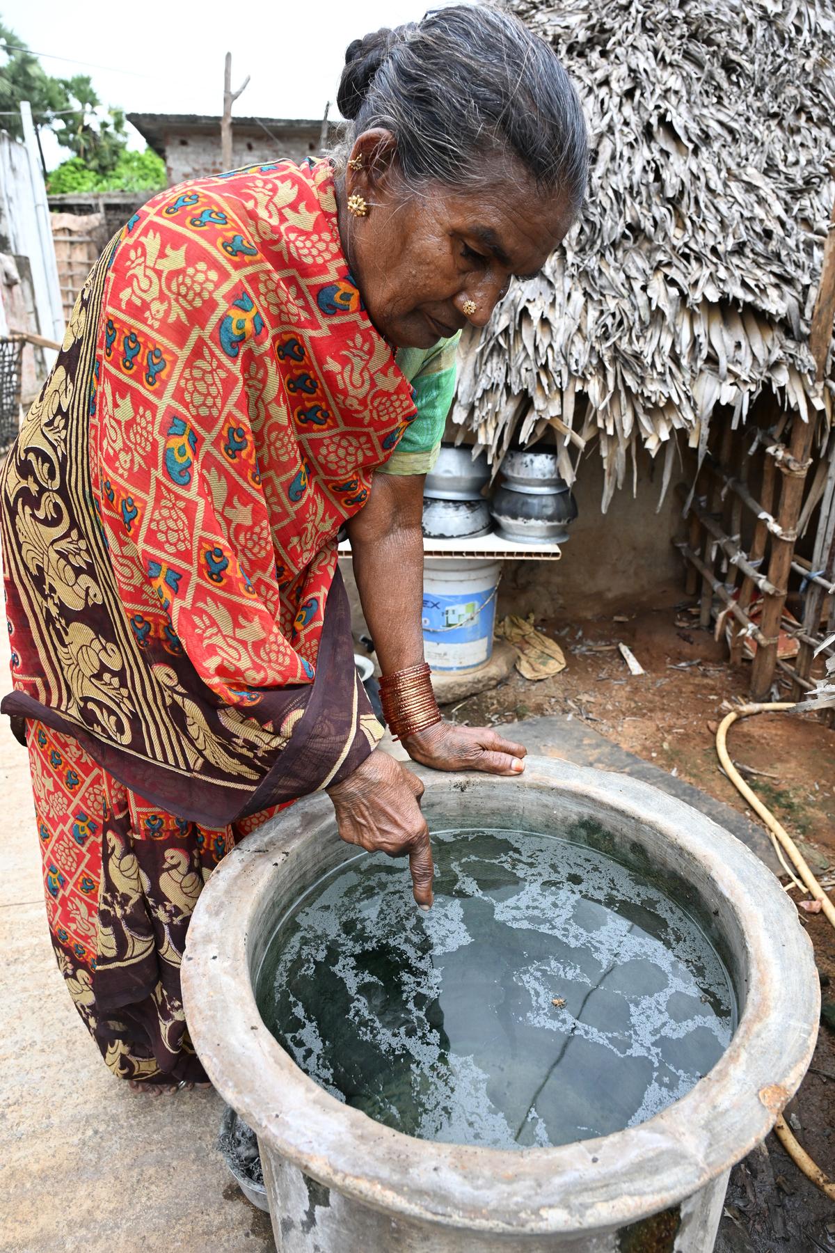 Polamma, a resident of Bhadrayyapeta village, showing the oily film on water stored near her house.