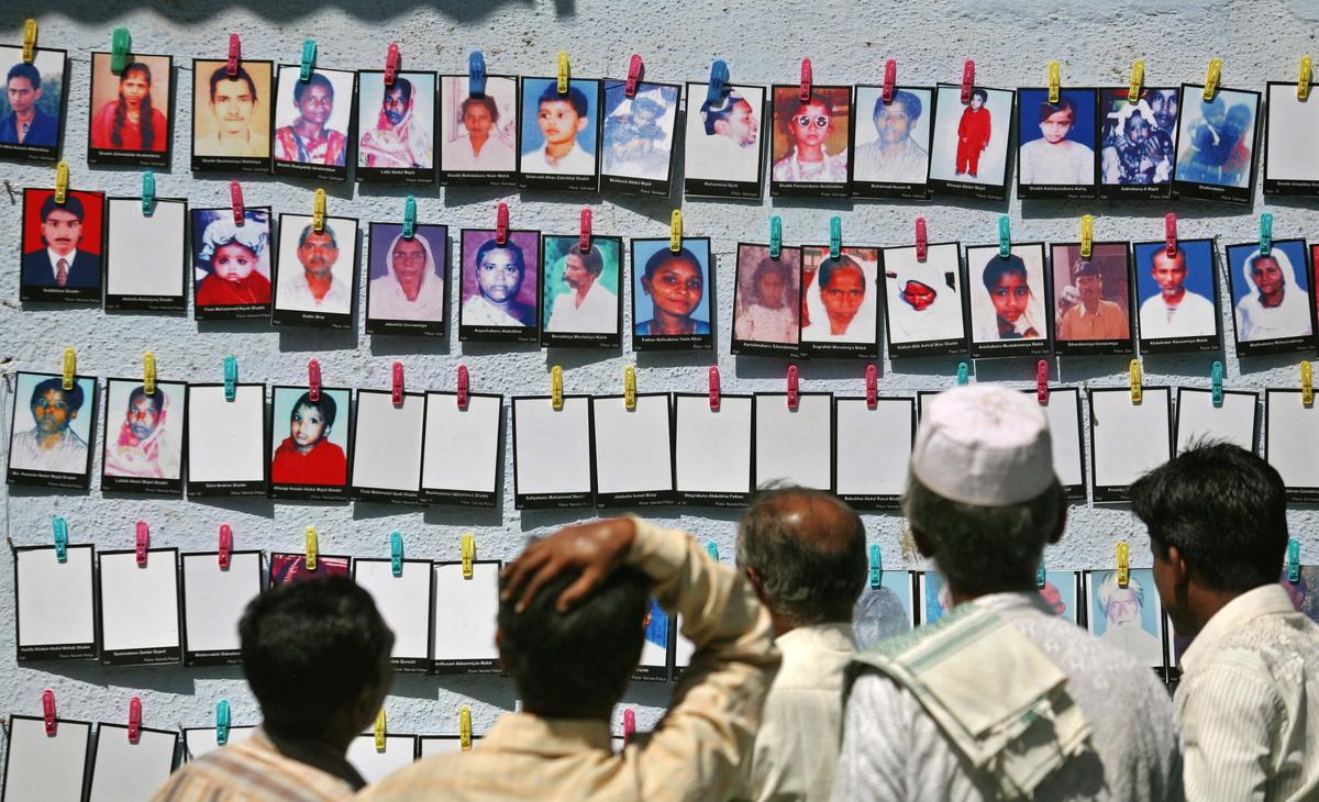 Survivors look at the photographs of Godhra riots victims, in Ahmedabad.