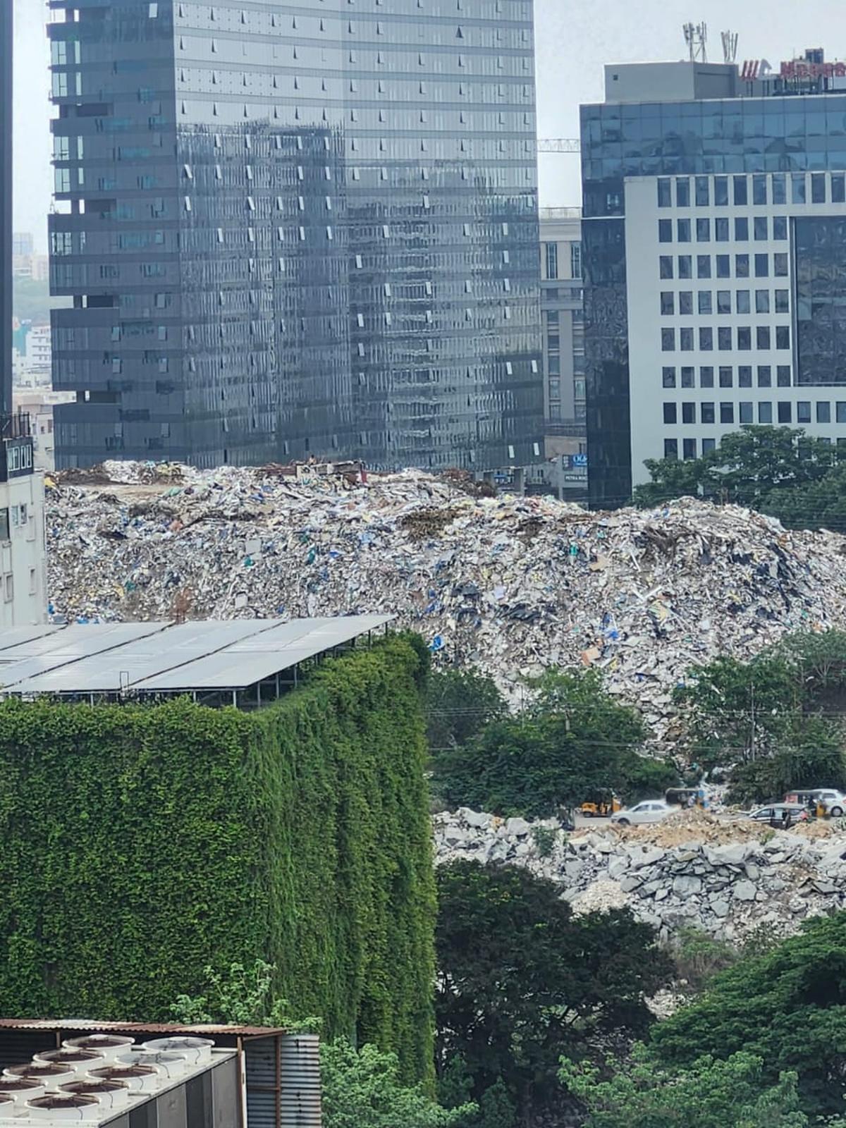 A massive heap of construction and demolition waste stands amid commercial towers near Hyderabad’s IT corridor in Gachibowli, highlighting the scale of the city’s growing urban waste challenge. Photo: Special Arrangement