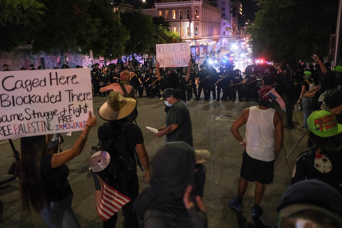 Demonstrators hold up signs in front of police officers during the No Kings protest against U.S. President Donald Trump’s policies, in Austin, Texas, U.S., June 14, 2025.  
