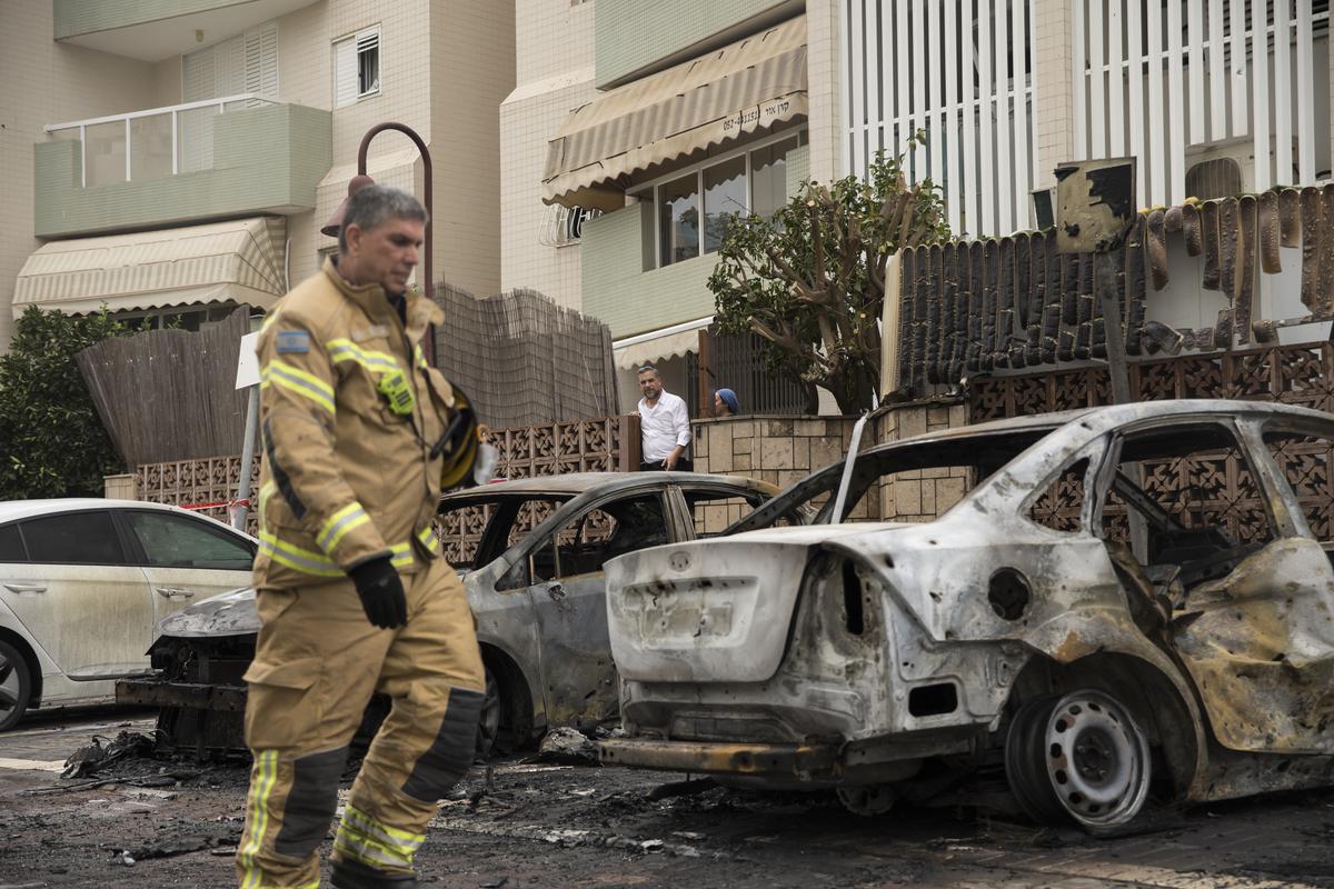 An Israeli fire fighter walks through the aftermath of burned cars after a rocket fired from the Gaza Strip hit Ashdod on October 9, 2023 in Ashdod Israel. 