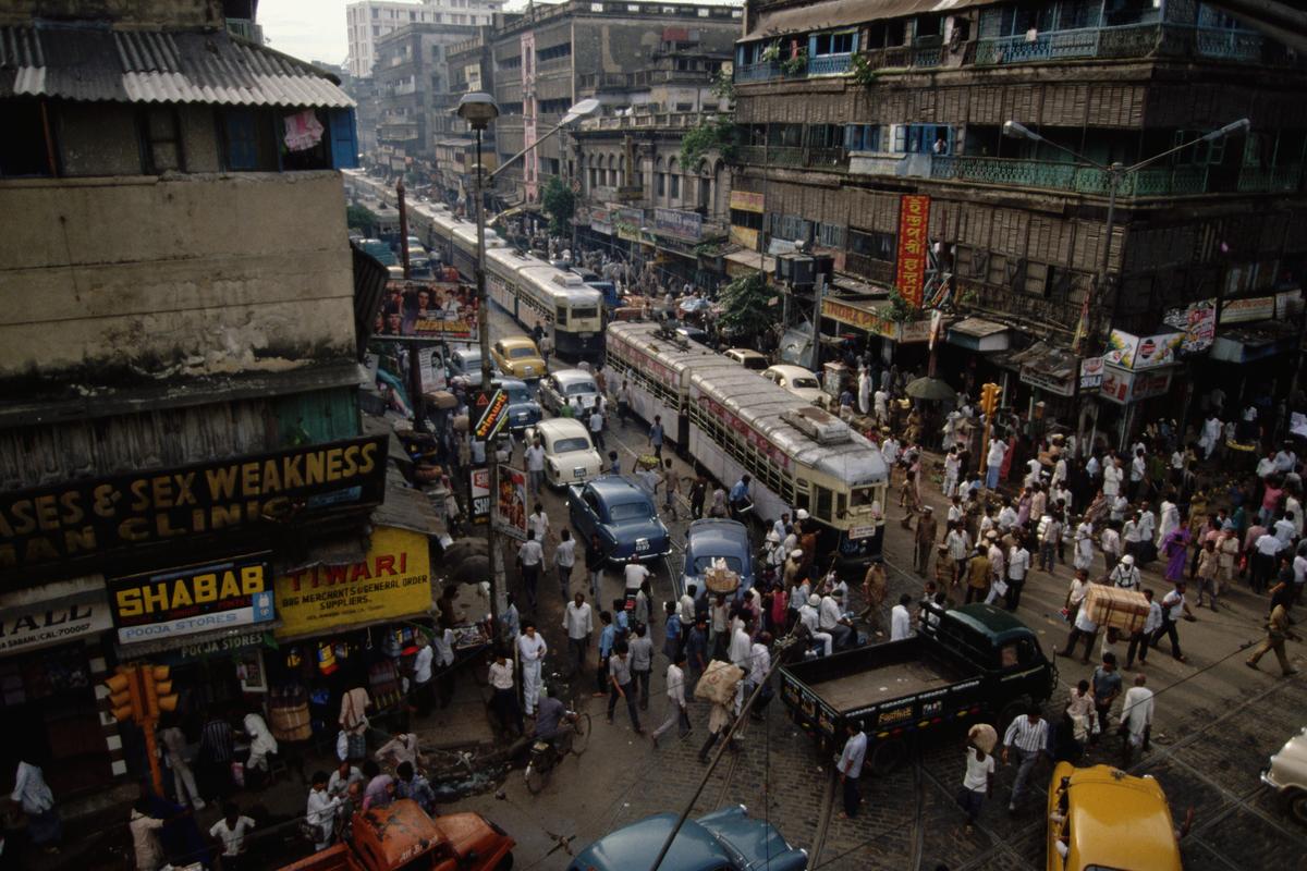 Pedestrians, trams, and automobiles clog a street in Park Circus