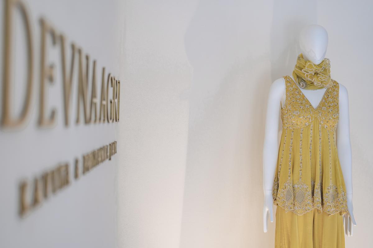 This vibrant yellow ensemble features a silk satin peplum kurta with sequins, pearls, zari and the french knot embroidery