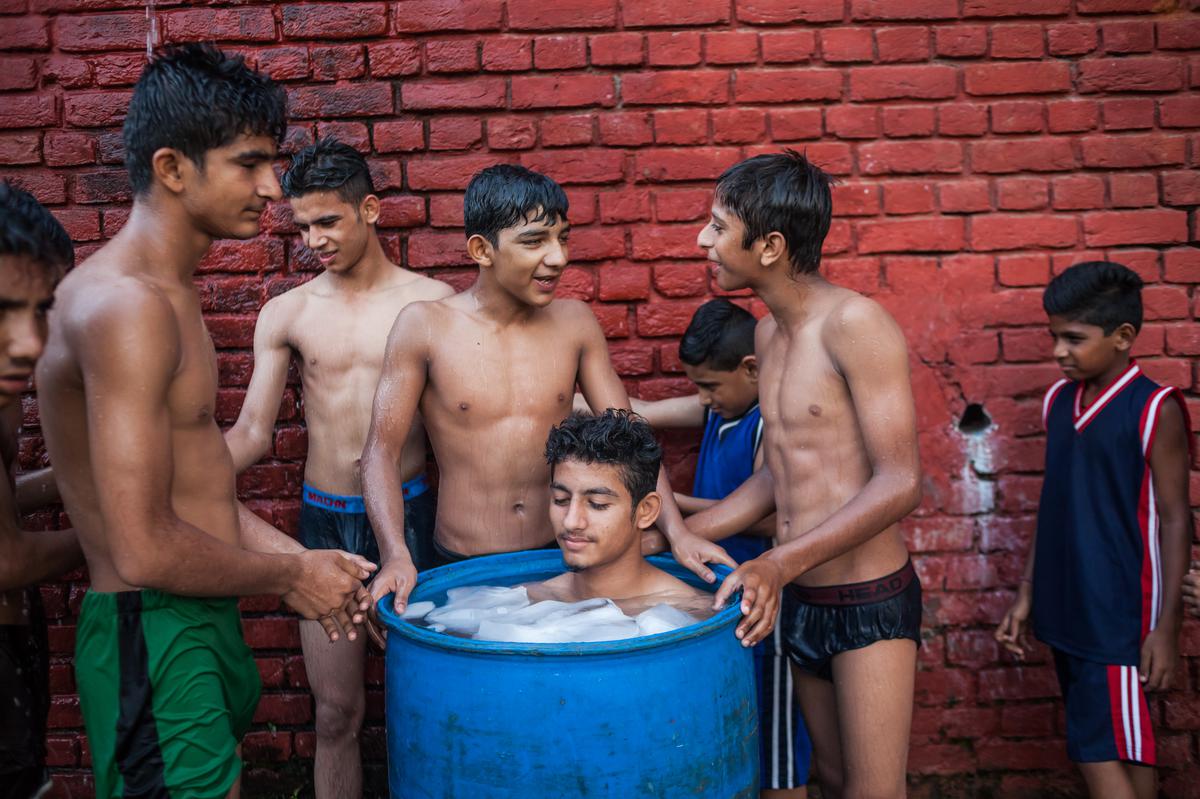 A Judoka takes an ‘ice bath’ in a drum as others wait for their turn at the end of their day’s practice at the Judo Training Centre in Gurdaspur