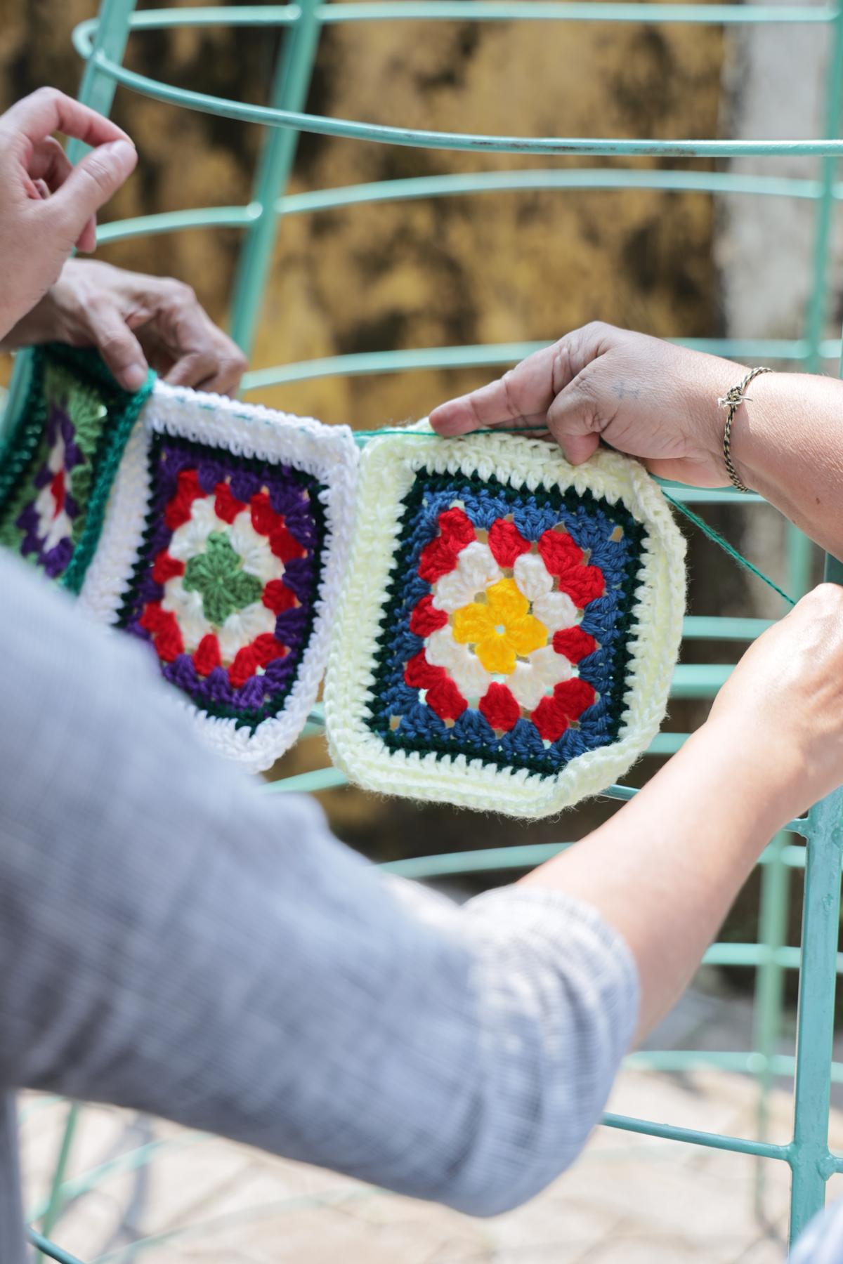 The members of the collective mount crochet squares on the frame of the tree 