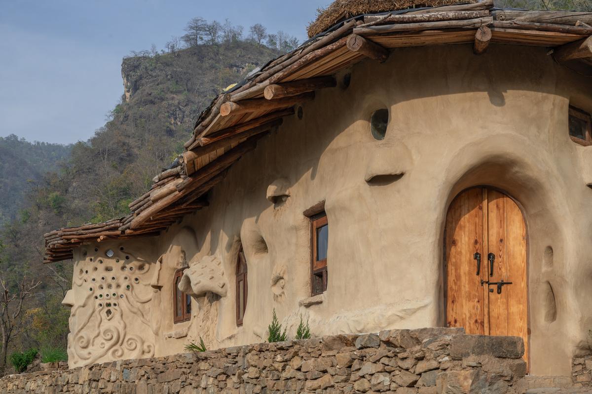 The 600 sq.ft. structure is created with earthen plaster cob walls, a stone arched gateway, and a reciprocal frame living roof