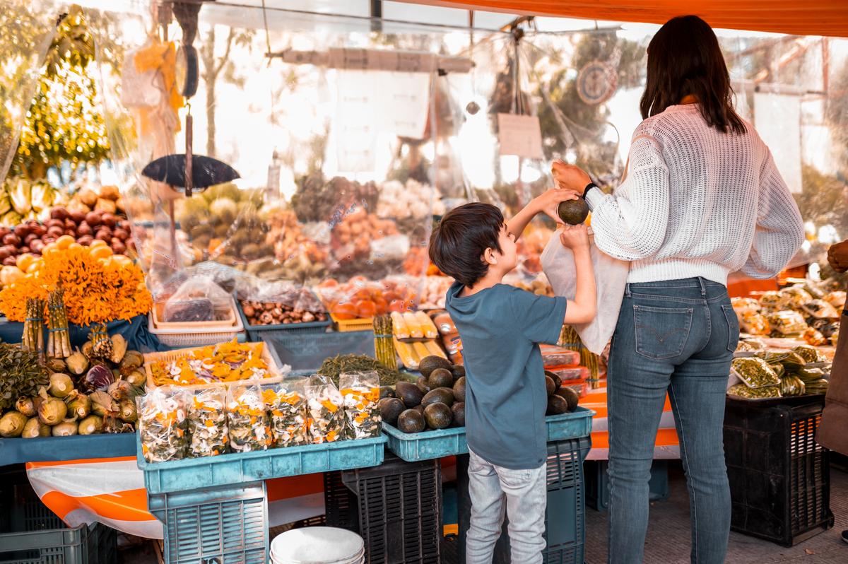 A child and his mother picking groceries at the farmers market