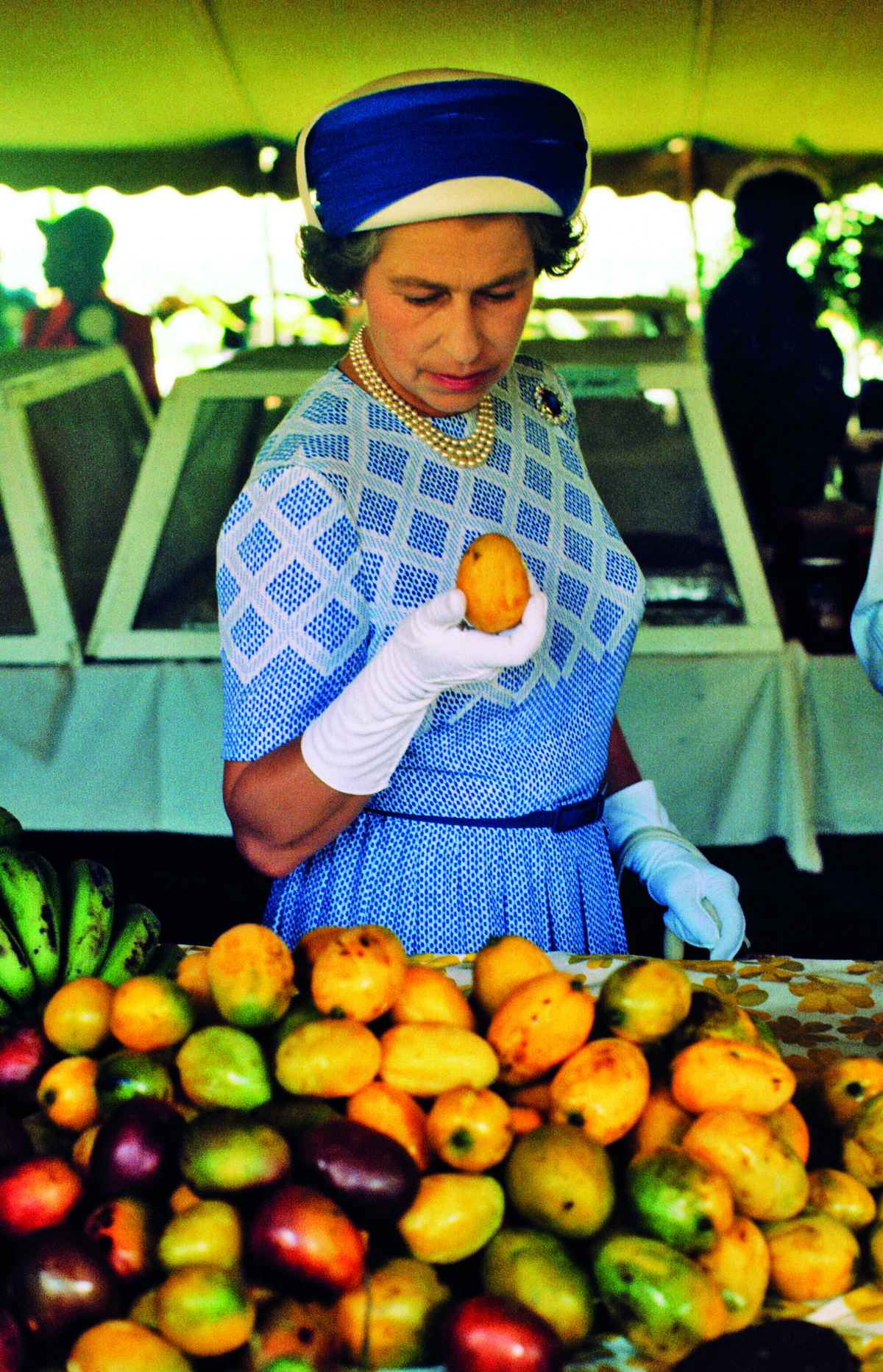 Queen Elizabeth II picks up a mango at a market in the British Virgin Islands, 1977