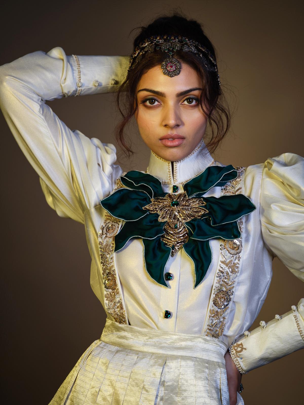 Sanyukta, a double tissue skirt set comes with a Victorian style blouse with puffed sleeves, embroidered suspenders, and an emerald silk collar bow Sanyukta, a double tissue skirt set comes with a Victorian style blouse with puffed sleeves, embroidered suspenders, and an emerald silk collar bow