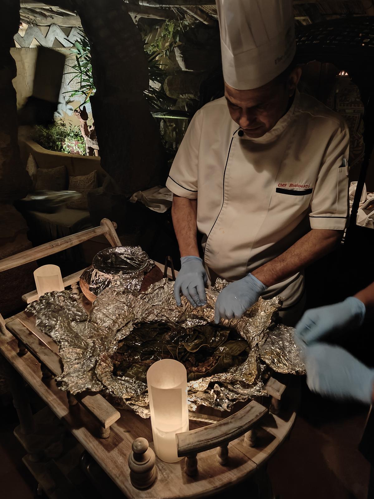 Chefs unwrap meat that has been slow cooked underground at Ajit Bhawan